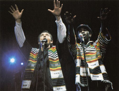 This photograph shows Peter Gabriel and Youssou NDour performing on stage. The Human Rights Concerts featured musicians such as Sting, The Police, Peter Gabriel, U2, Bruce Springsteen, Radiohead, Joan Baez, and many others. Over 1,250,000 people around the world attended these concerts in person, and millions more experienced them on television and radio. This series of 28 rock concerts presented worldwide between1986-1998 raised funds for and awareness of Amnesty International worldwide. This photograph was taken during one of the Human Rights Now tour concerts which was a twenty-concert world tour held over a six-week period in September–October 1988. The tour commemorated the 40th anniversary of the Universal Declaration of Human Rights. The tour starred Bruce Springsteen & the E Street Band, Sting and Peter Gabriel with Tracy Chapman and Youssou N'Dour. Guest musicians who made appearances during the tour included Bono, Joan Baez, k.d. lang and Pat Metheney. The twenty concerts took place in fifteen different countries on five continents (Europe, Asia, Africa, North America and South America). In each country the concert also featured performances by popular local musicians.
